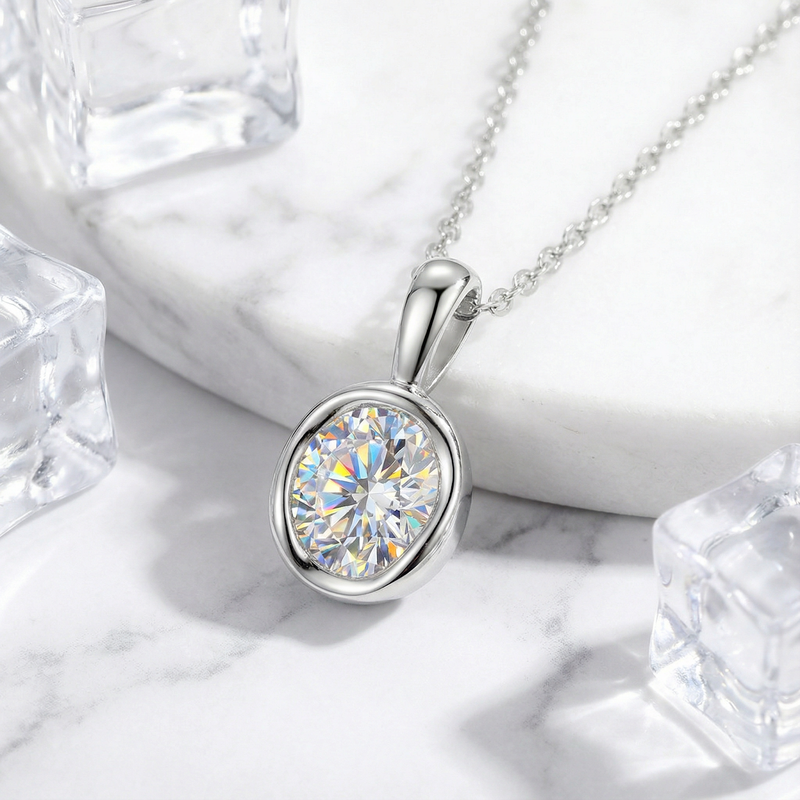 Close-up of a 1CT round simulated diamond in a sterling silver bezel pendant on a white marble background.