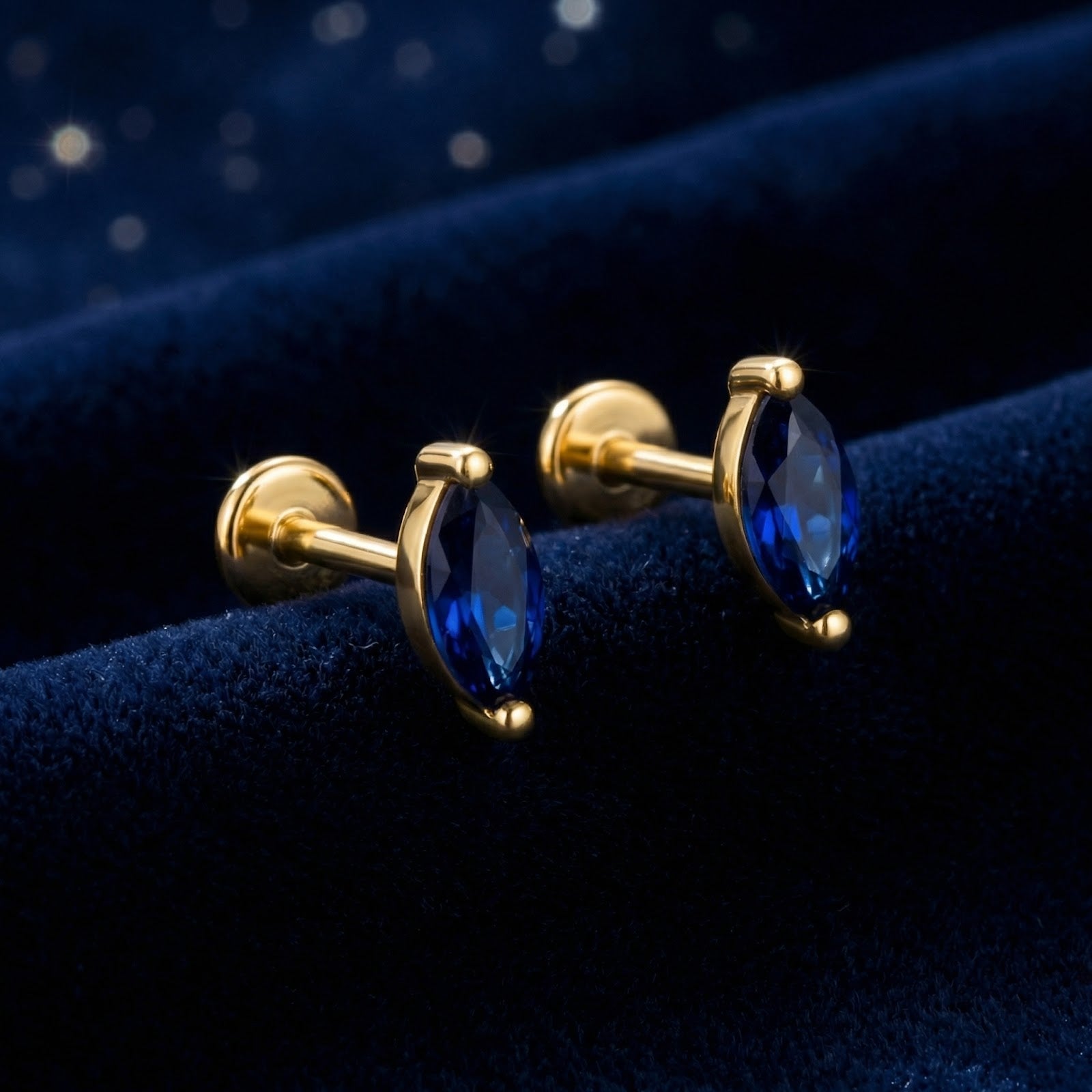 Side profile of marquise cut simulated sapphire gold vermeil stud earrings with flat back posts on blue velvet.