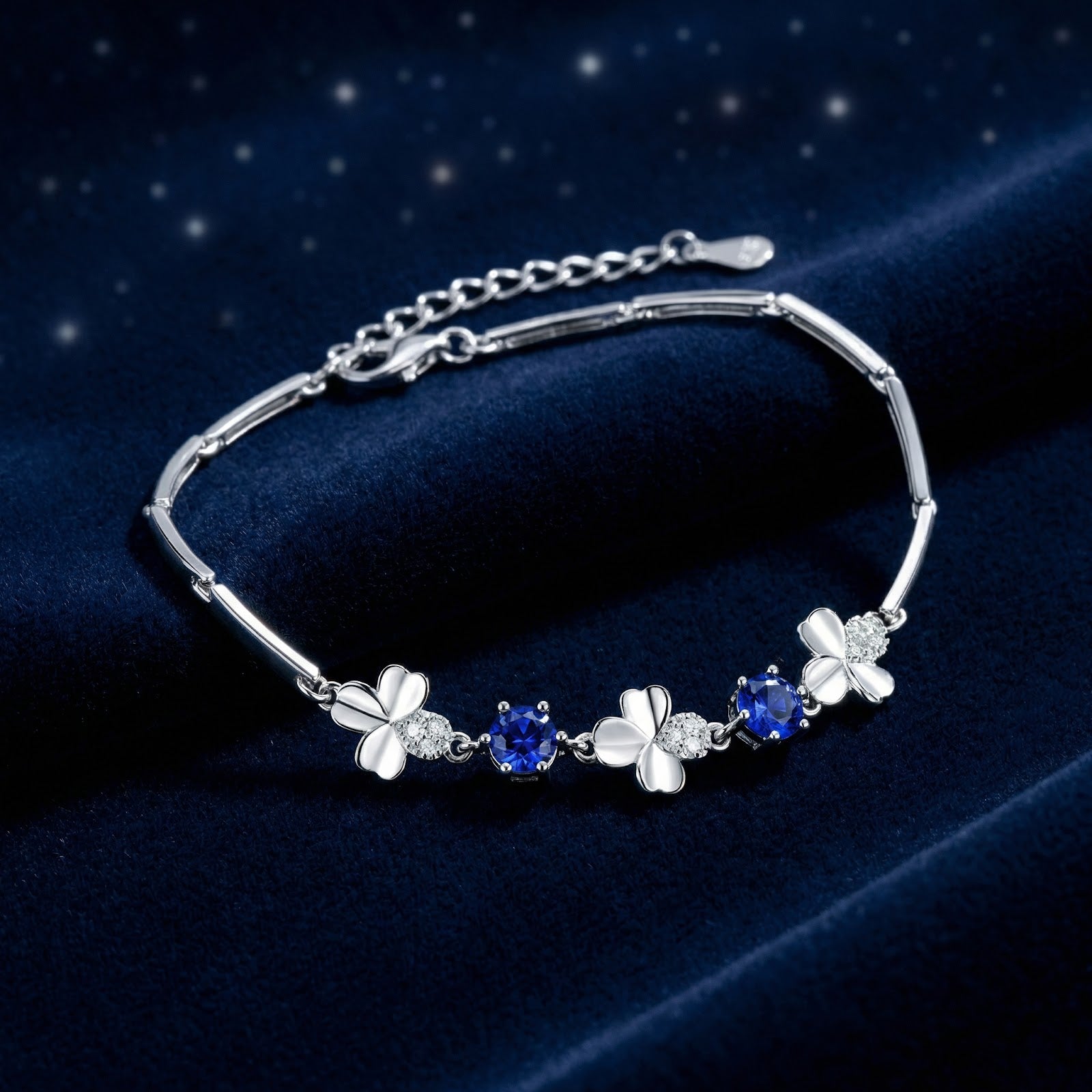 S925 sterling silver clover bracelet with round-cut blue simulated sapphires on a dark blue velvet background.
