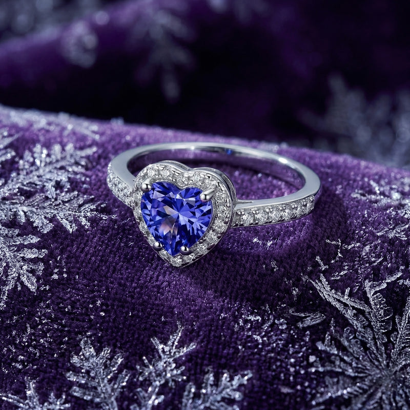 Heart-shaped simulated tanzanite silver ring with a diamond halo on purple velvet with snowflake patterns.