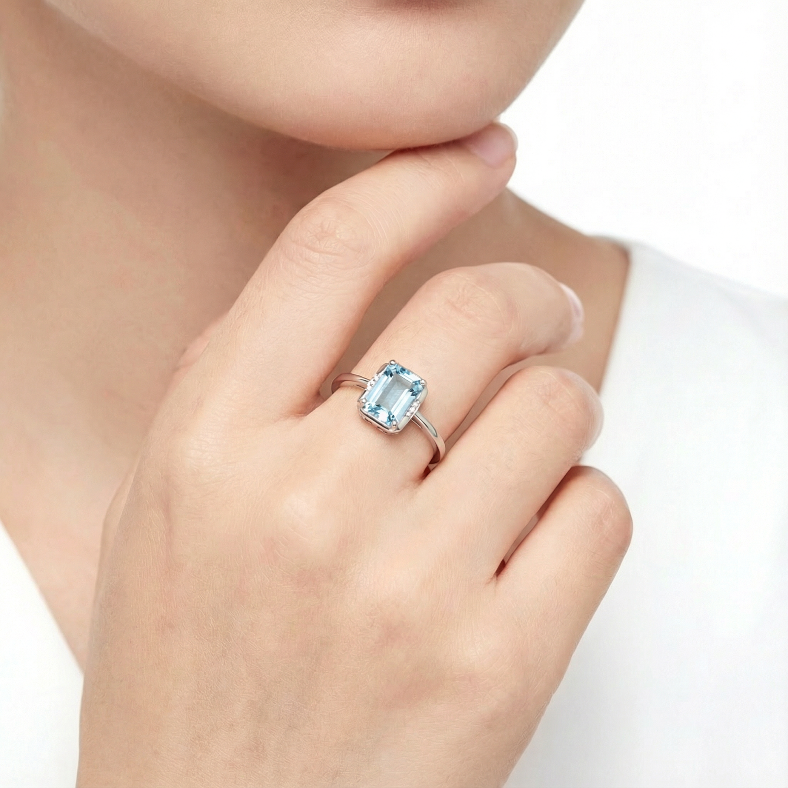 Woman wearing an emerald cut simulated aquamarine sterling silver ring on her finger.