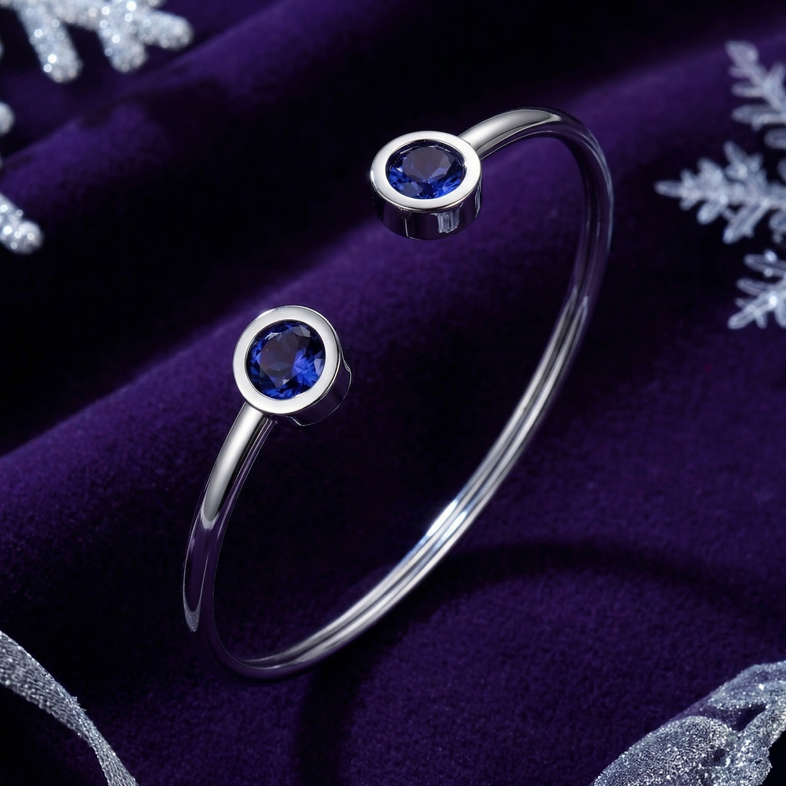 Silver stainless steel Veralis cuff with round simulated tanzanite stones on a purple velvet background.