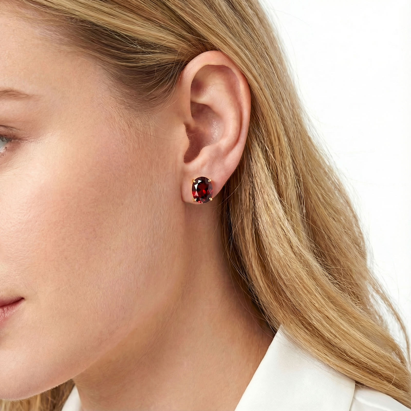 Close-up of a Seraphine 18K gold vermeil stud earring with a red simulated garnet on a model's ear.