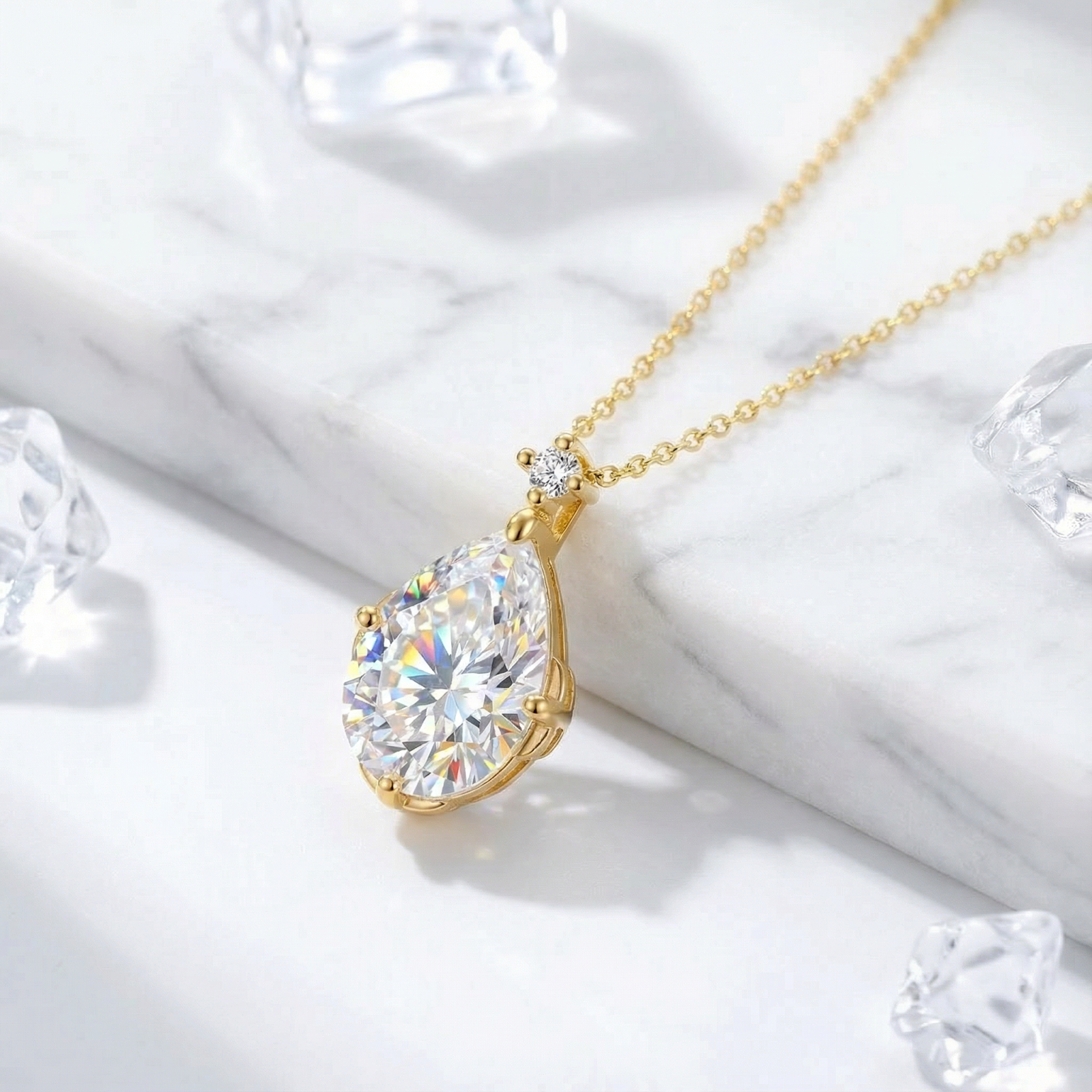 Pear-cut zirconia teardrop necklace in 18K gold vermeil on a marble surface with decorative ice cubes.