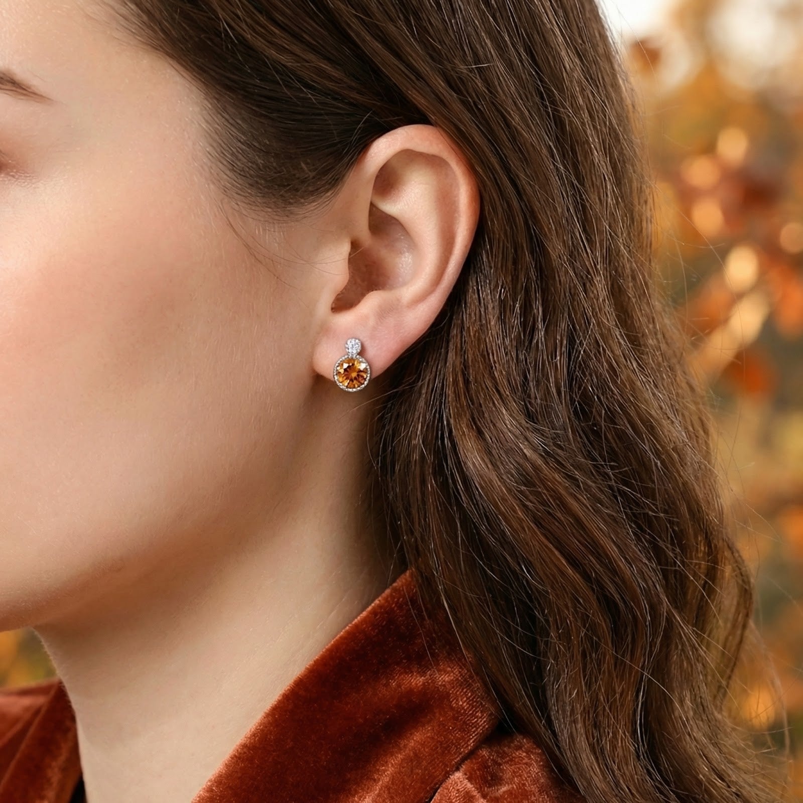 Woman wearing a round-cut simulated topaz drop earring in S925 sterling silver against an autumnal background.