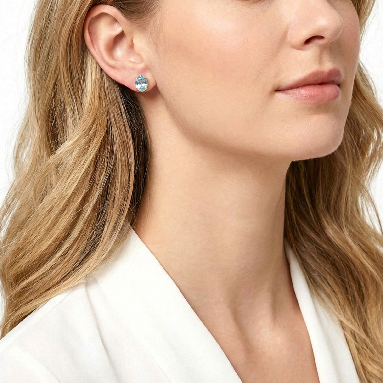 Profile view of a model wearing the Marisca oval simulated aquamarine sterling silver stud earrings.