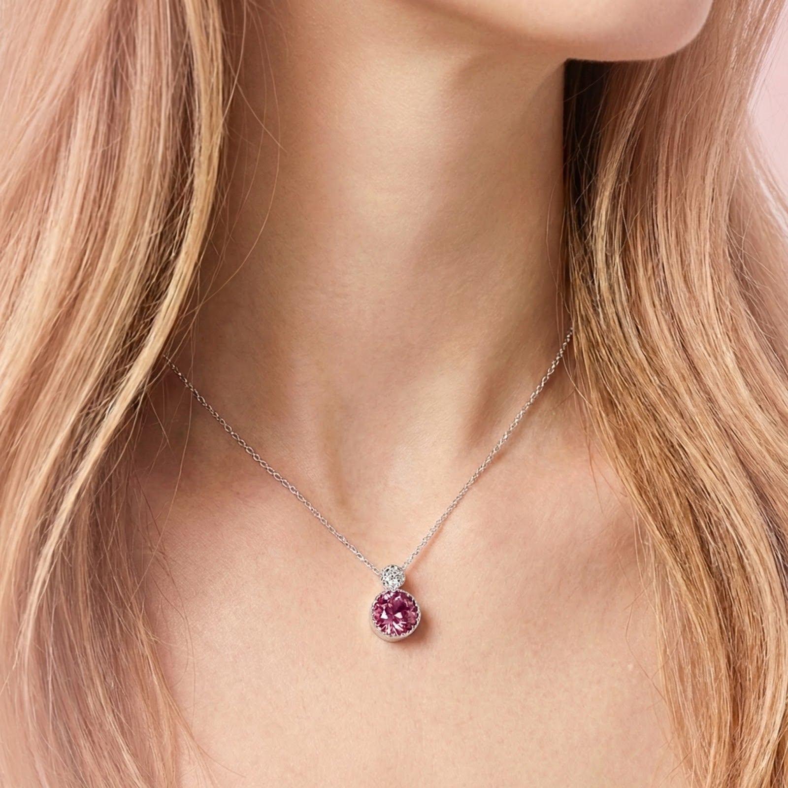 Close-up of the S925 sterling silver necklace with a round-cut simulated pink tourmaline pendant on a model's neck.