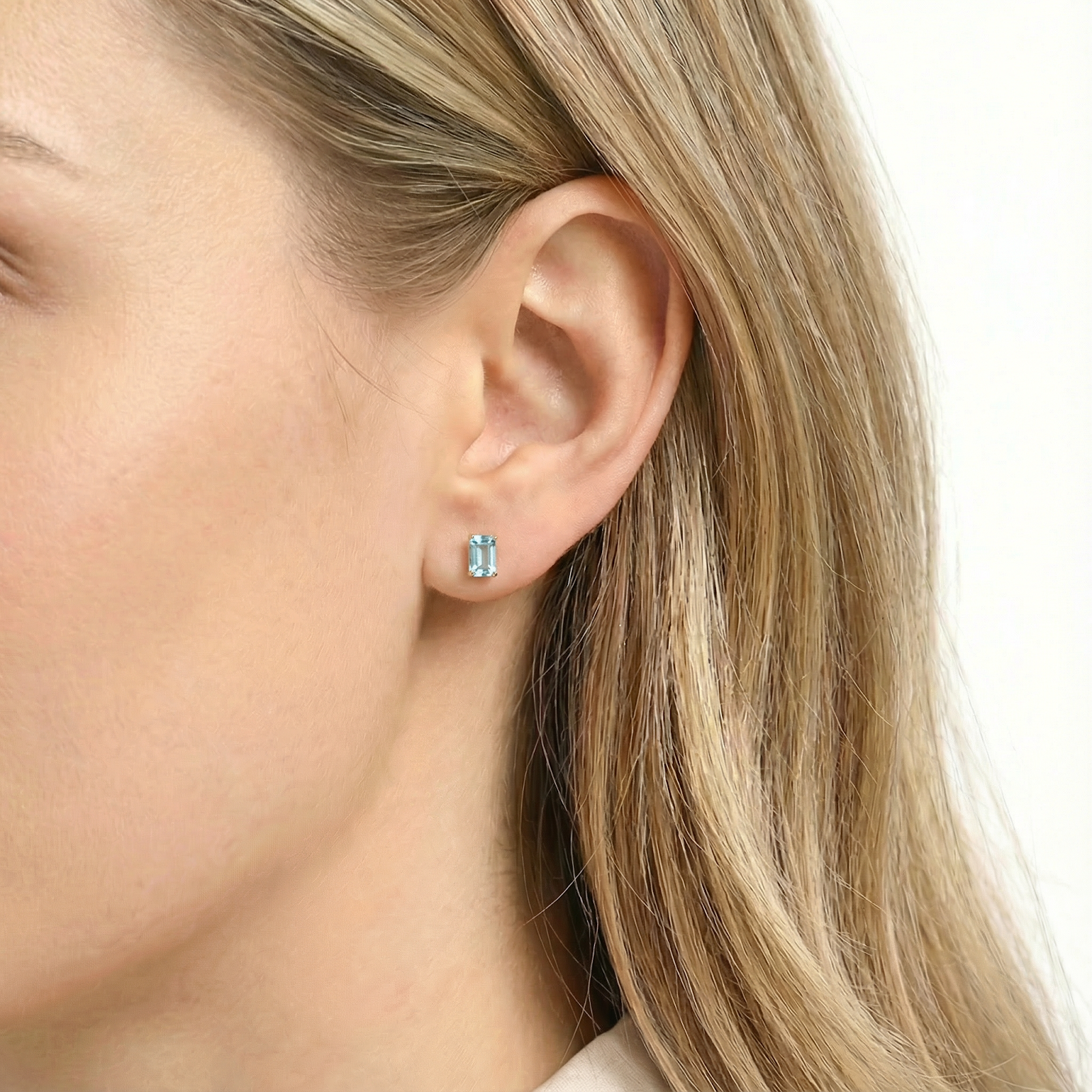 Side view of a model wearing the Alysia baguette-cut simulated aquamarine earring in 18K gold vermeil.