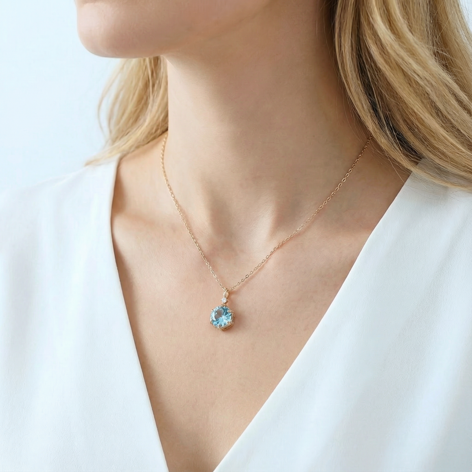 March birthstone hexagon cut aquamarine necklace in 18K gold vermeil worn by a model in a white top.
