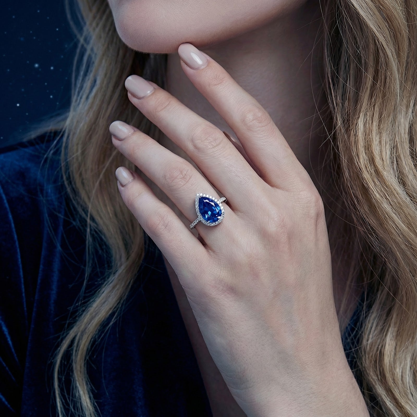 Woman wearing the pear cut simulated sapphire sterling silver halo ring on her ring finger.