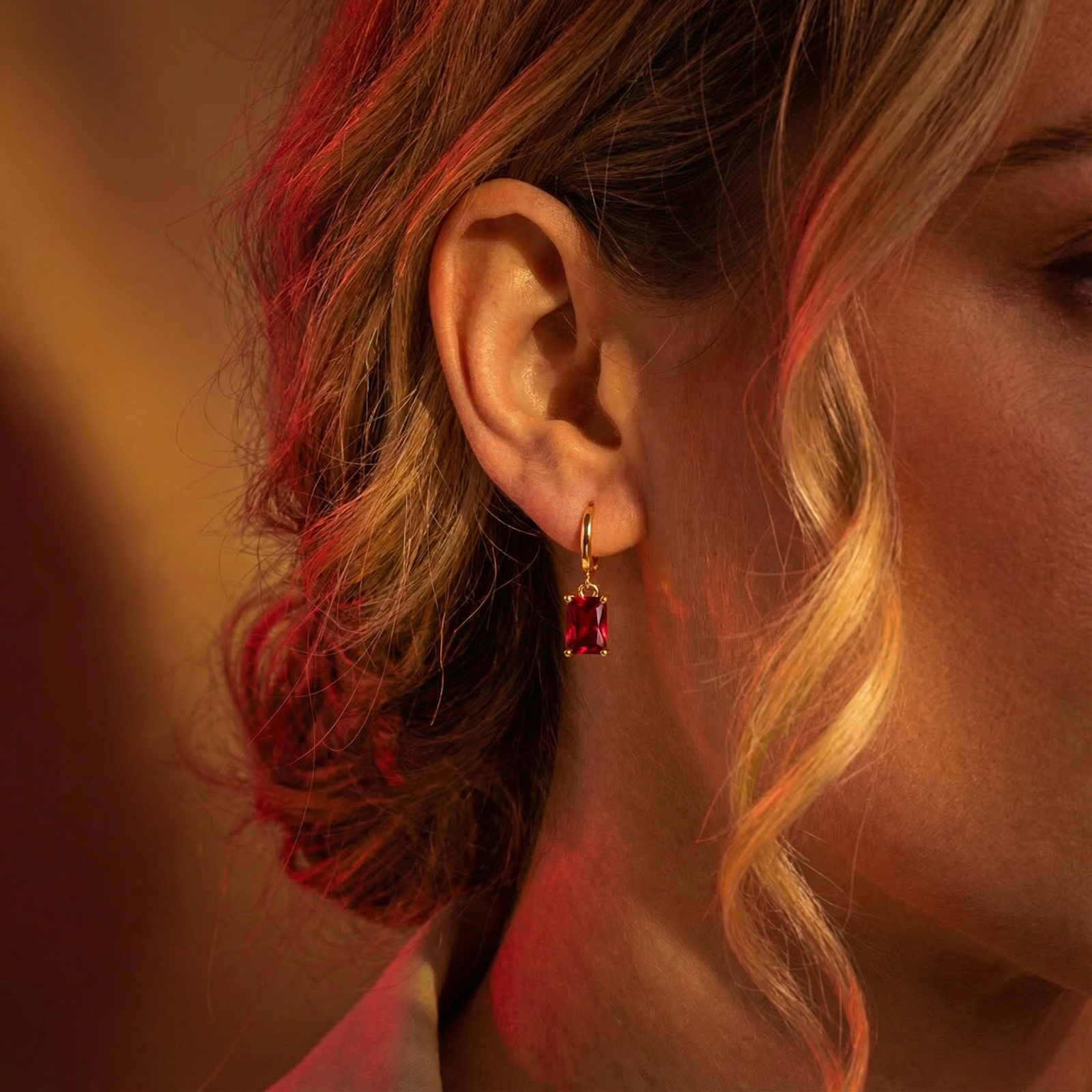 Side view of a woman wearing the 18K gold vermeil Solaraea drop earring with a red ruby.