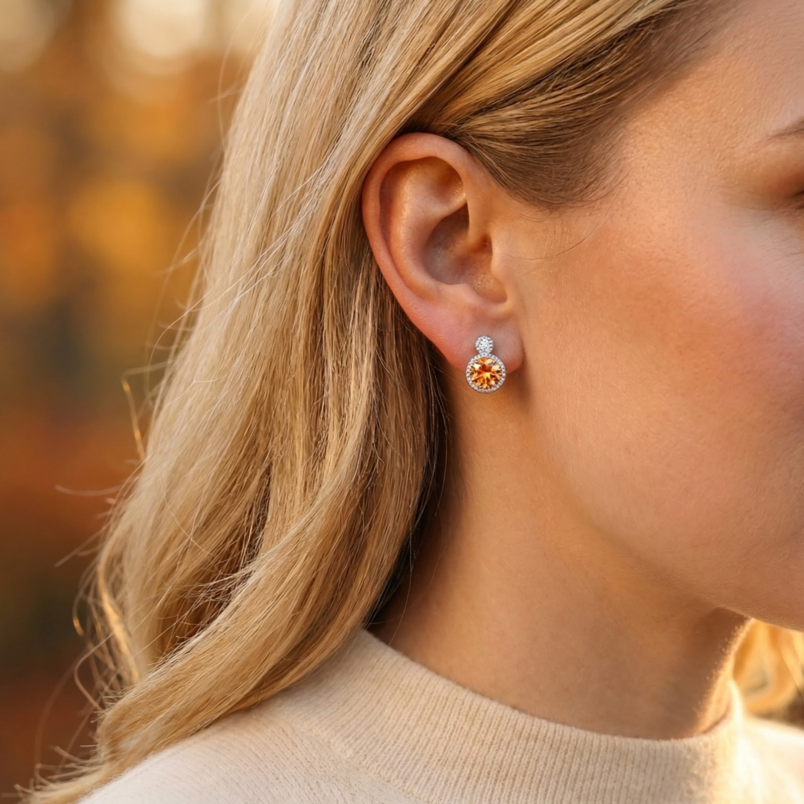 Close-up of a blonde model wearing the Caelara round-cut simulated topaz drop earring in sterling silver.