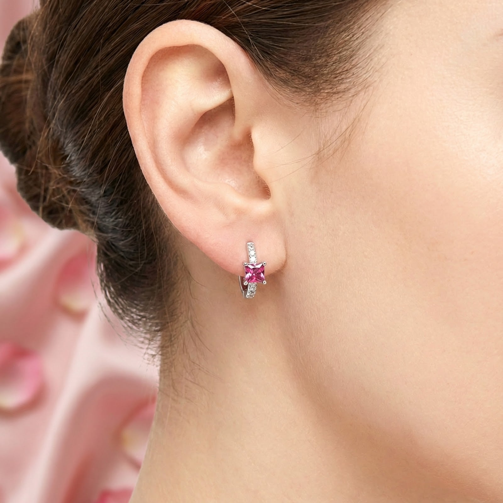 Close-up of a square-cut pink tourmaline huggie earring in sterling silver worn on a model's ear.