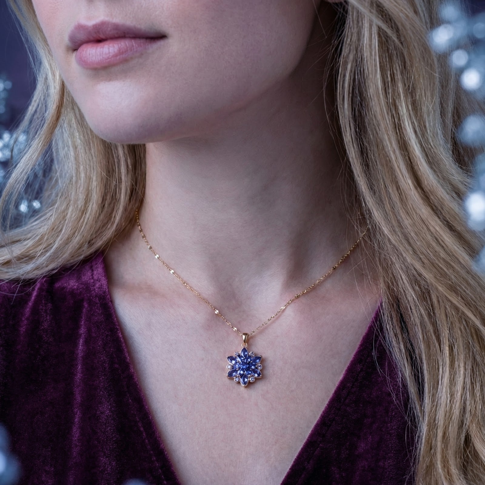 Model wearing the gold finish stainless steel Auralis Bloom necklace with blue-violet simulated tanzanite stones.