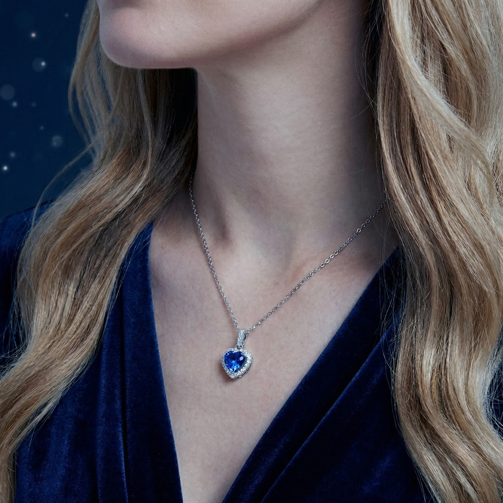 Side view of a model wearing the heart-cut simulated sapphire halo necklace in sterling silver.