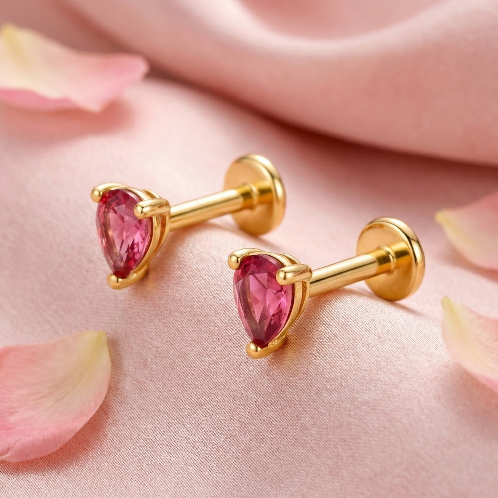 Pear-cut simulated pink tourmaline stud earrings in 18K gold vermeil resting on pink silk with rose petals.