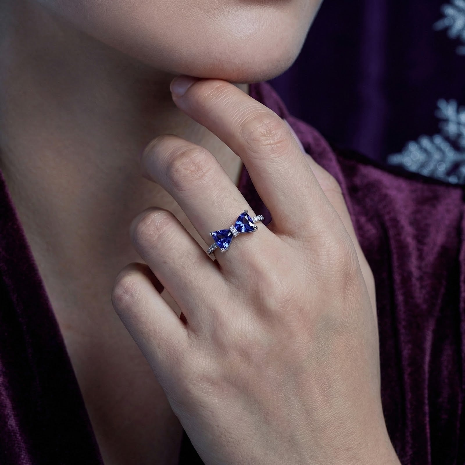 Evelia bow ring in sterling silver with blue-violet simulated tanzanite worn on a woman's finger.