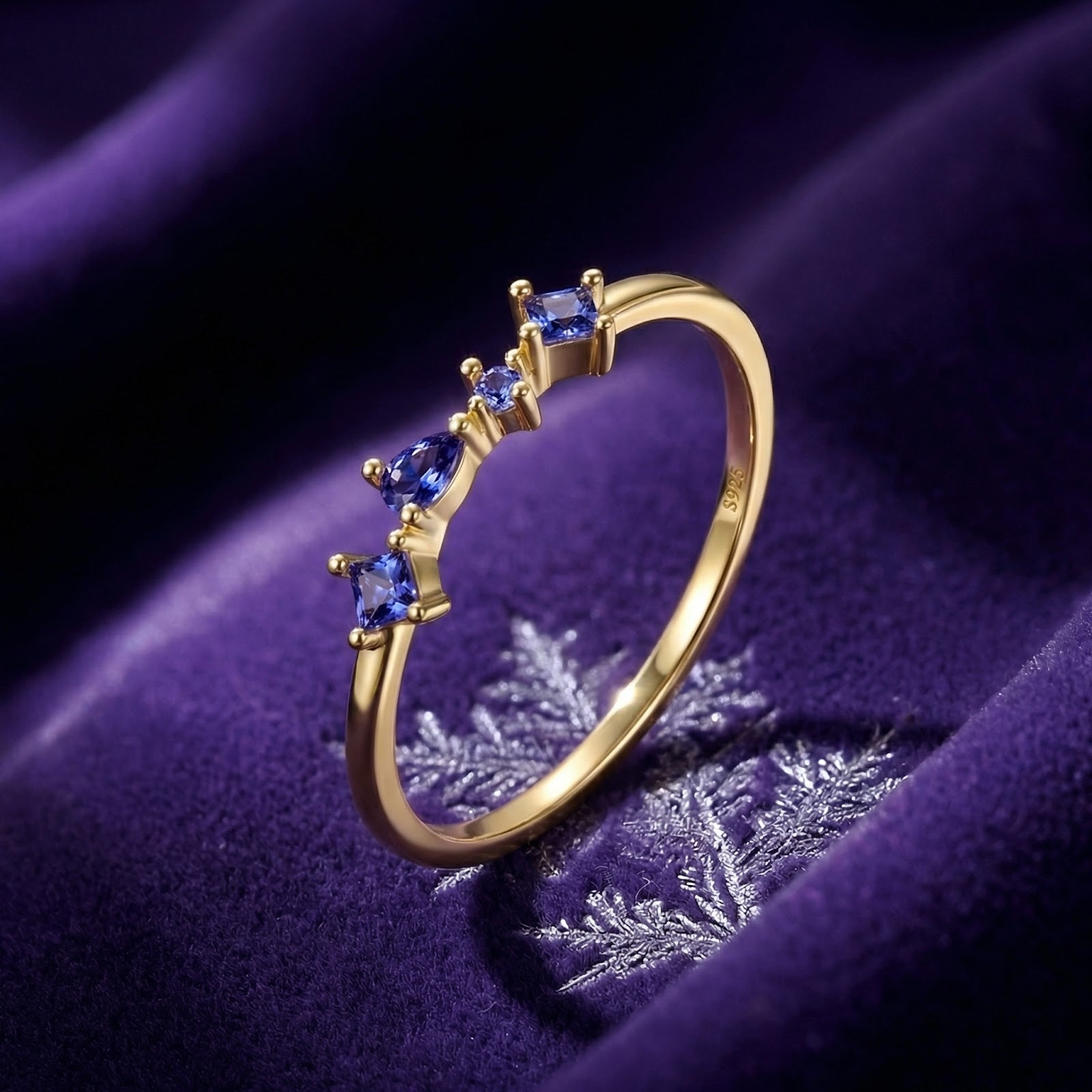 Nerisara cascade ring in 18K gold vermeil with pear and square cut simulated tanzanite on purple velvet with snowflake.