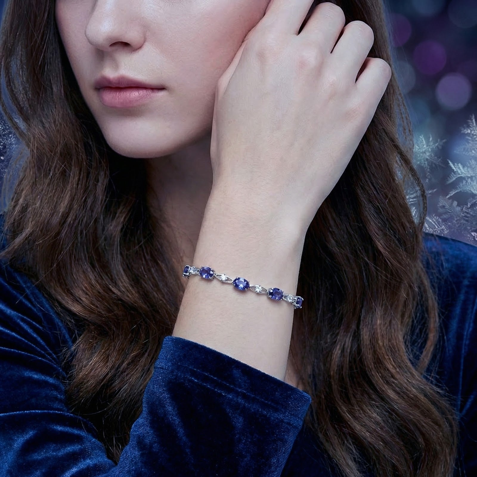 Woman wearing the sterling silver Lyranise station bracelet with blue simulated tanzanite stones.