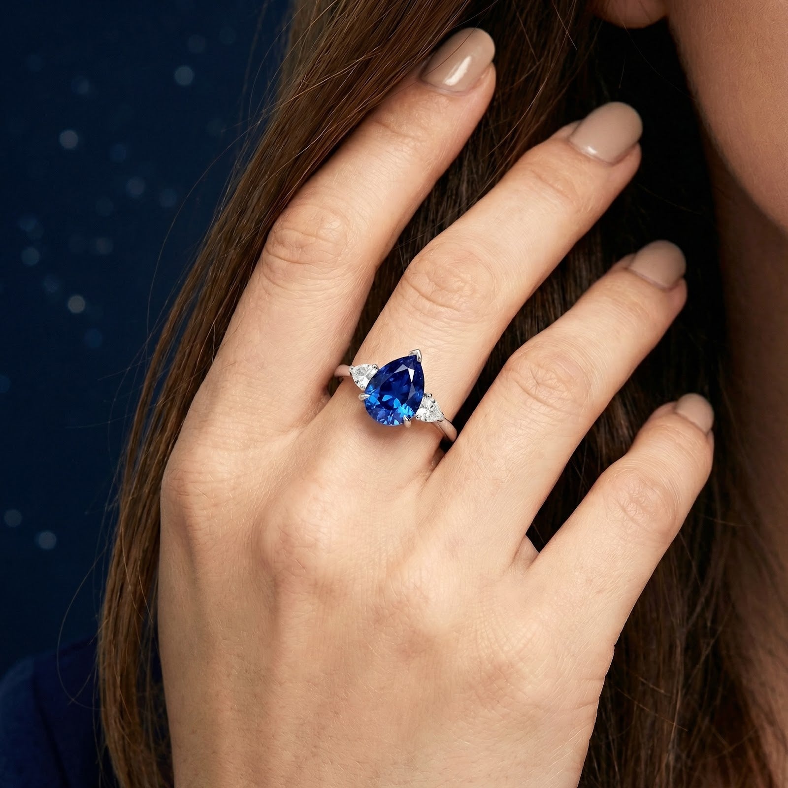 Woman wearing the pear-cut simulated sapphire sterling silver ring on her ring finger.