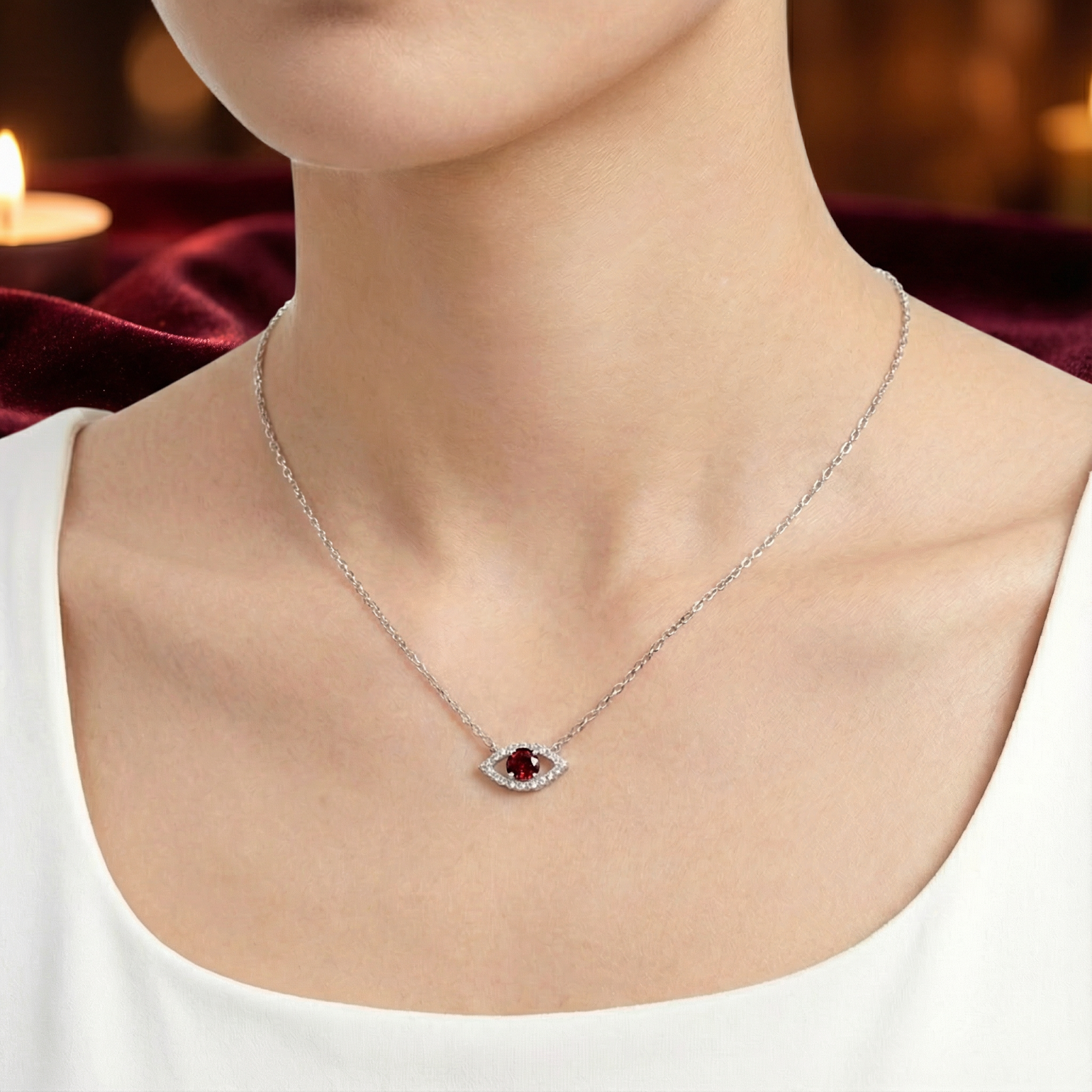 Model wearing the sterling silver Nyx Eye necklace with a round red garnet center stone on a delicate chain.