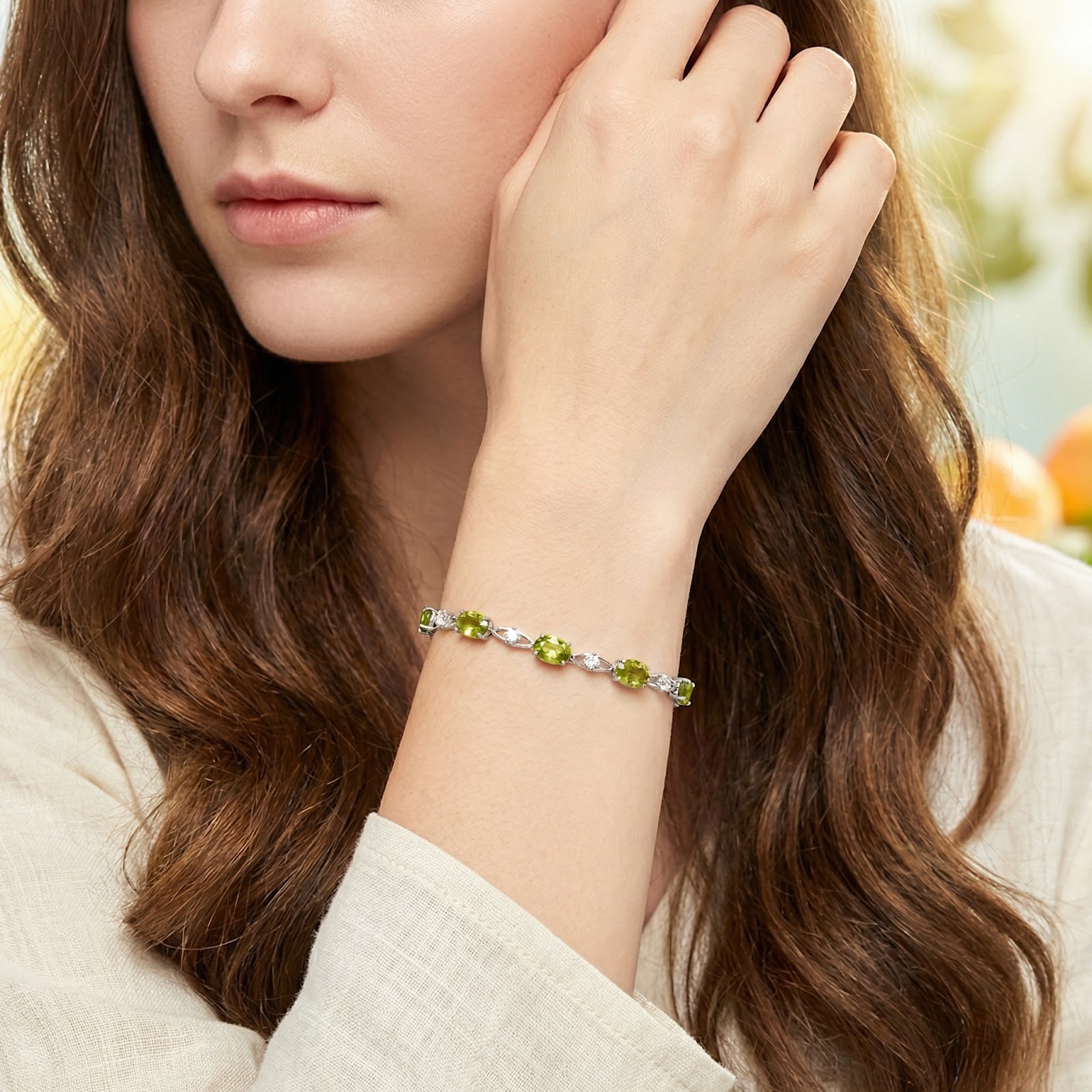 Woman wearing the Lysaraea station bracelet in S925 sterling silver with vibrant oval simulated peridot stones.