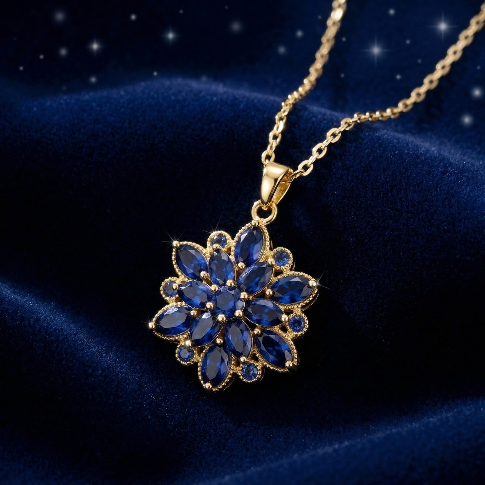 Gold finish stainless steel floral necklace with marquise simulated sapphires on blue velvet.