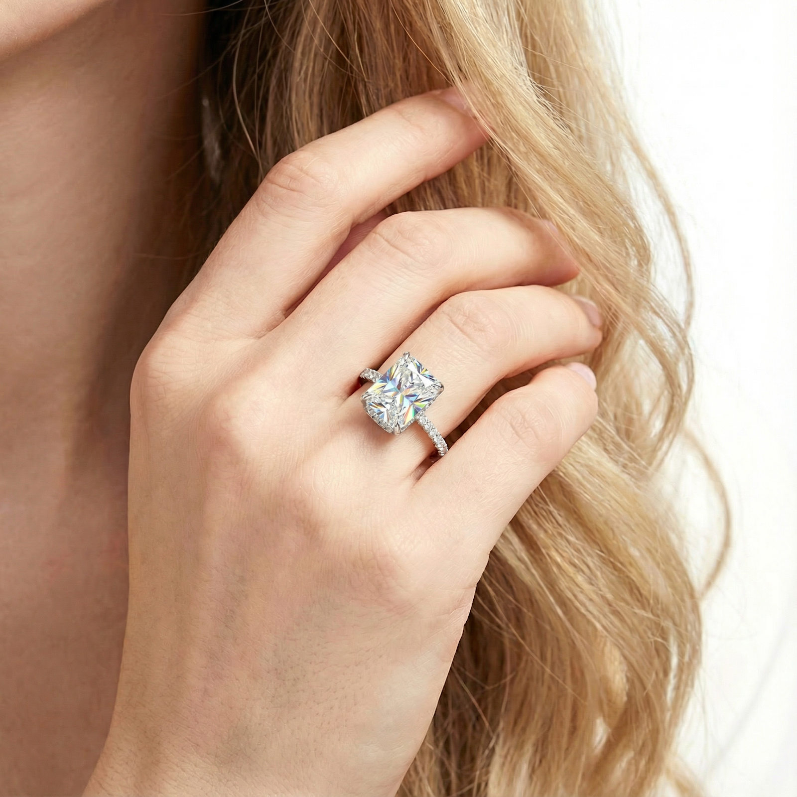 Radiant cut simulated diamond ring in S925 sterling silver worn on a model's hand touching her hair.