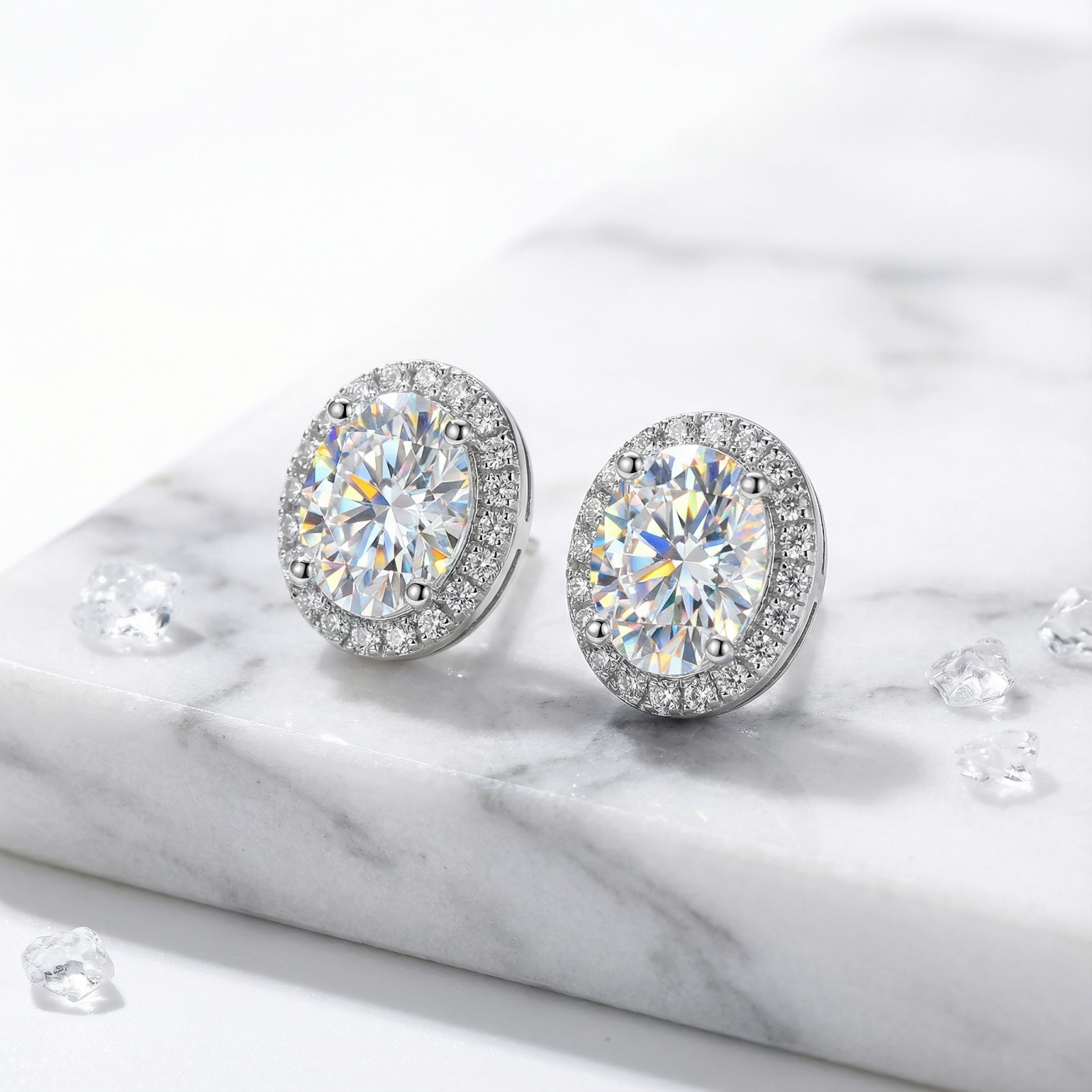 Round cut zirconia halo stud earrings in sterling silver on a white marble surface.