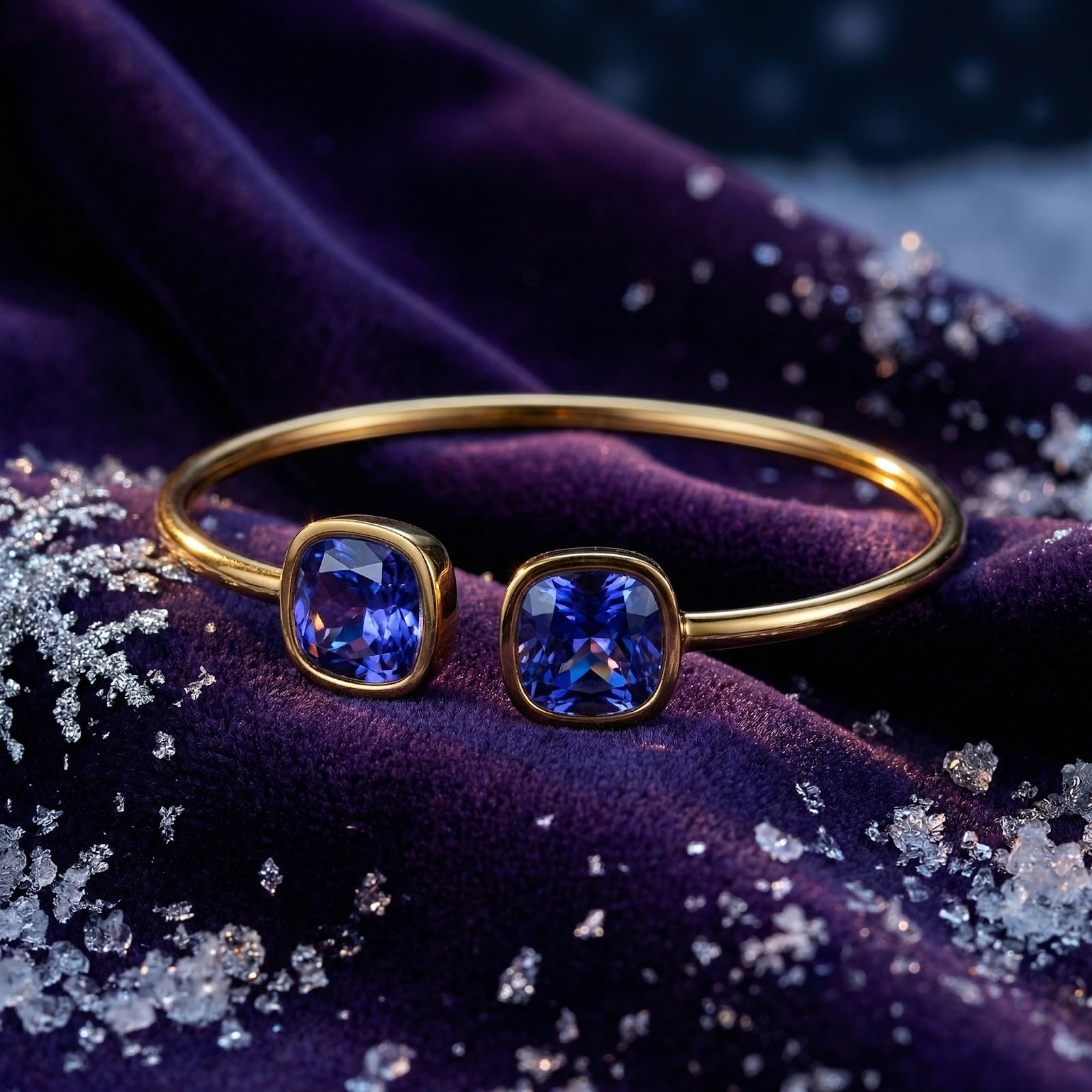 Front view of gold Nerina bangle featuring two cushion-cut blue simulated tanzanite stones on purple velvet.