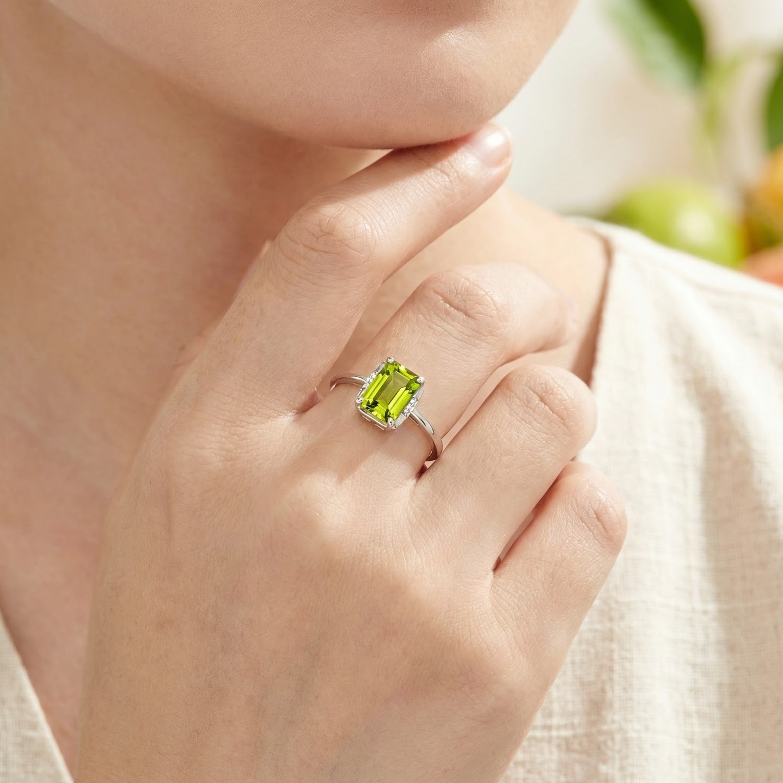 Emerald cut simulated peridot sterling silver ring worn on a model's hand for a close-up view.
