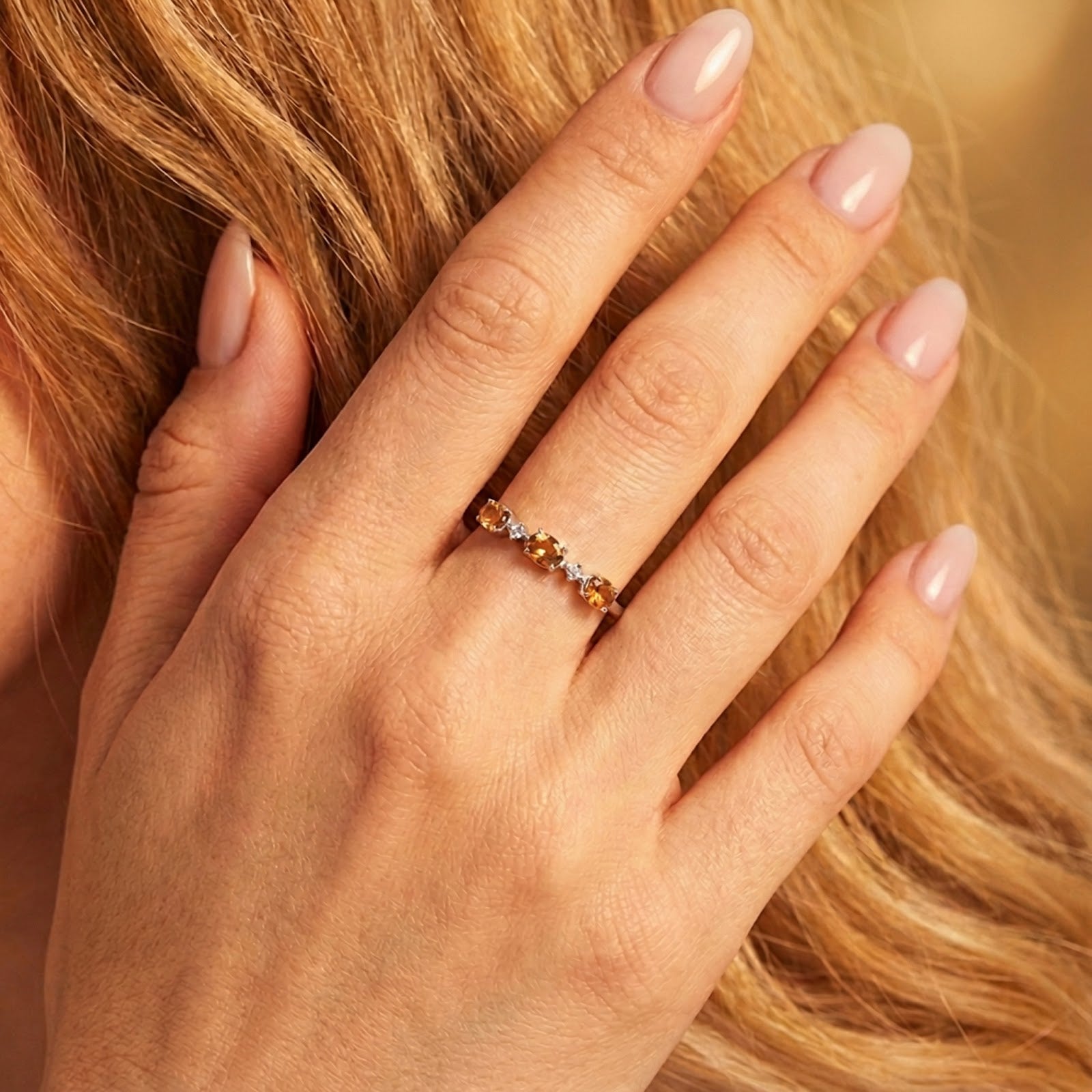 Top-down view of the Evalise sterling silver ring with oval simulated topaz stones worn on a woman's hand.