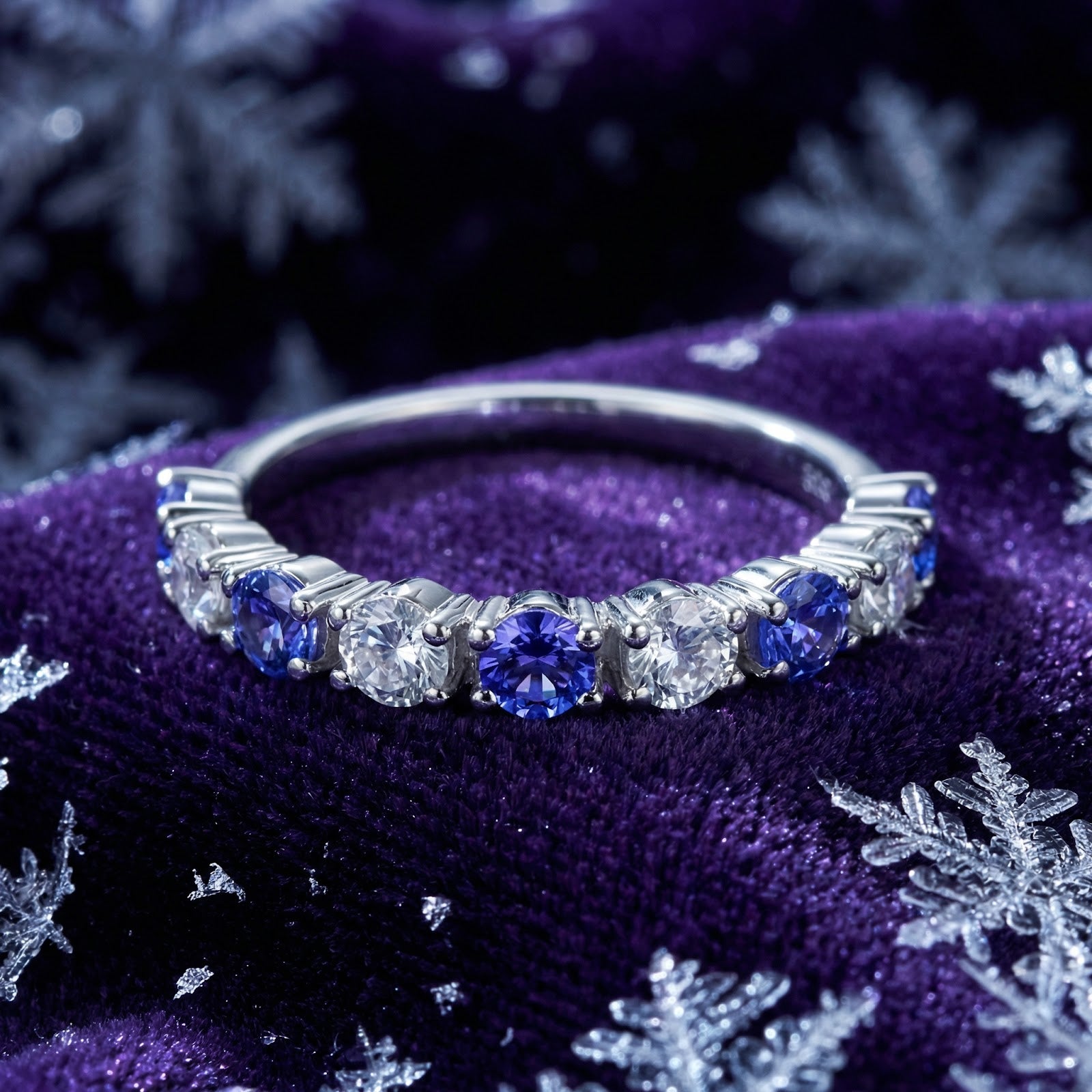 Kyrianne Row sterling silver ring with round-cut simulated tanzanite and clear stones on purple velvet with snowflakes.