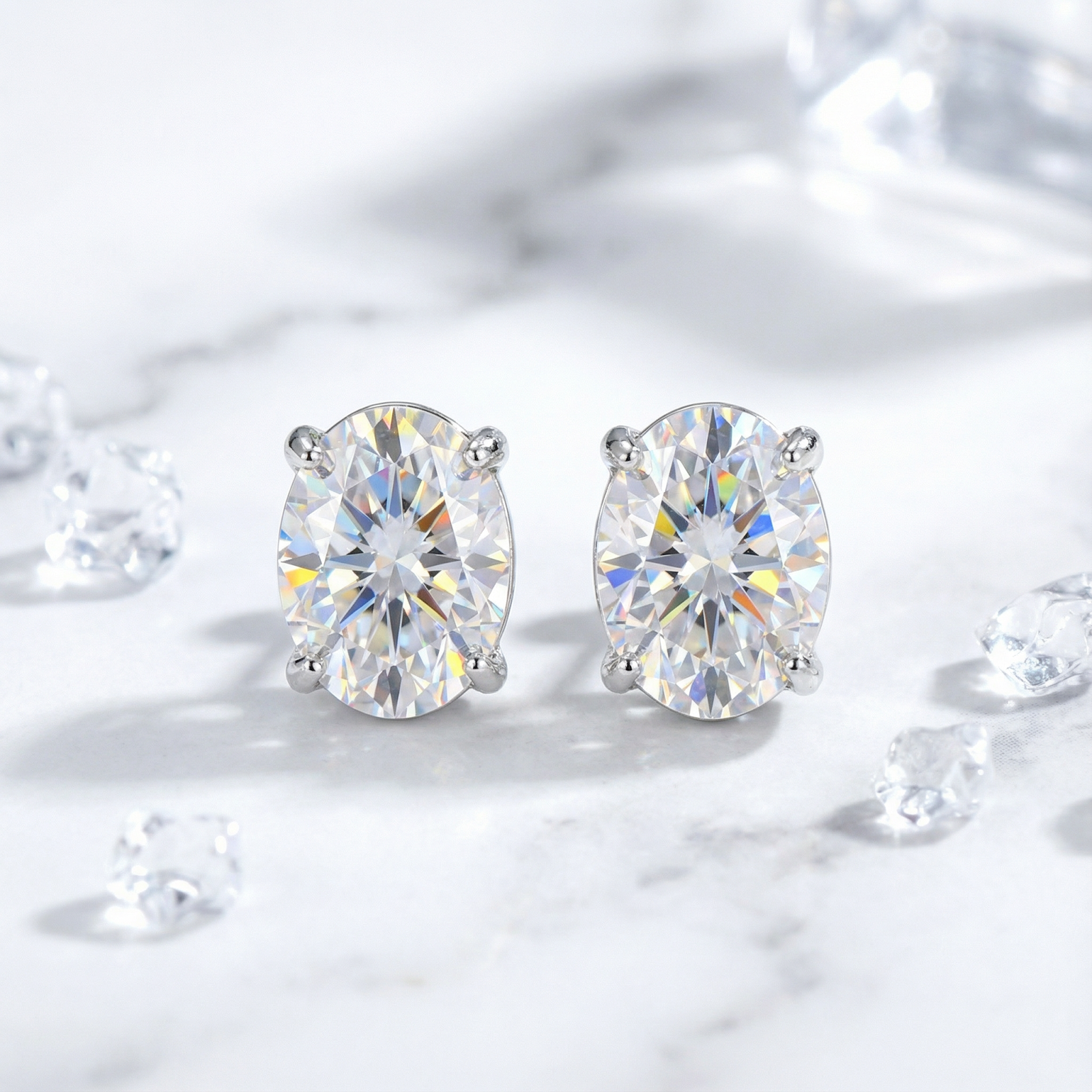 Front view of oval cut zirconia stud earrings in silver four-prong settings on a marble background.