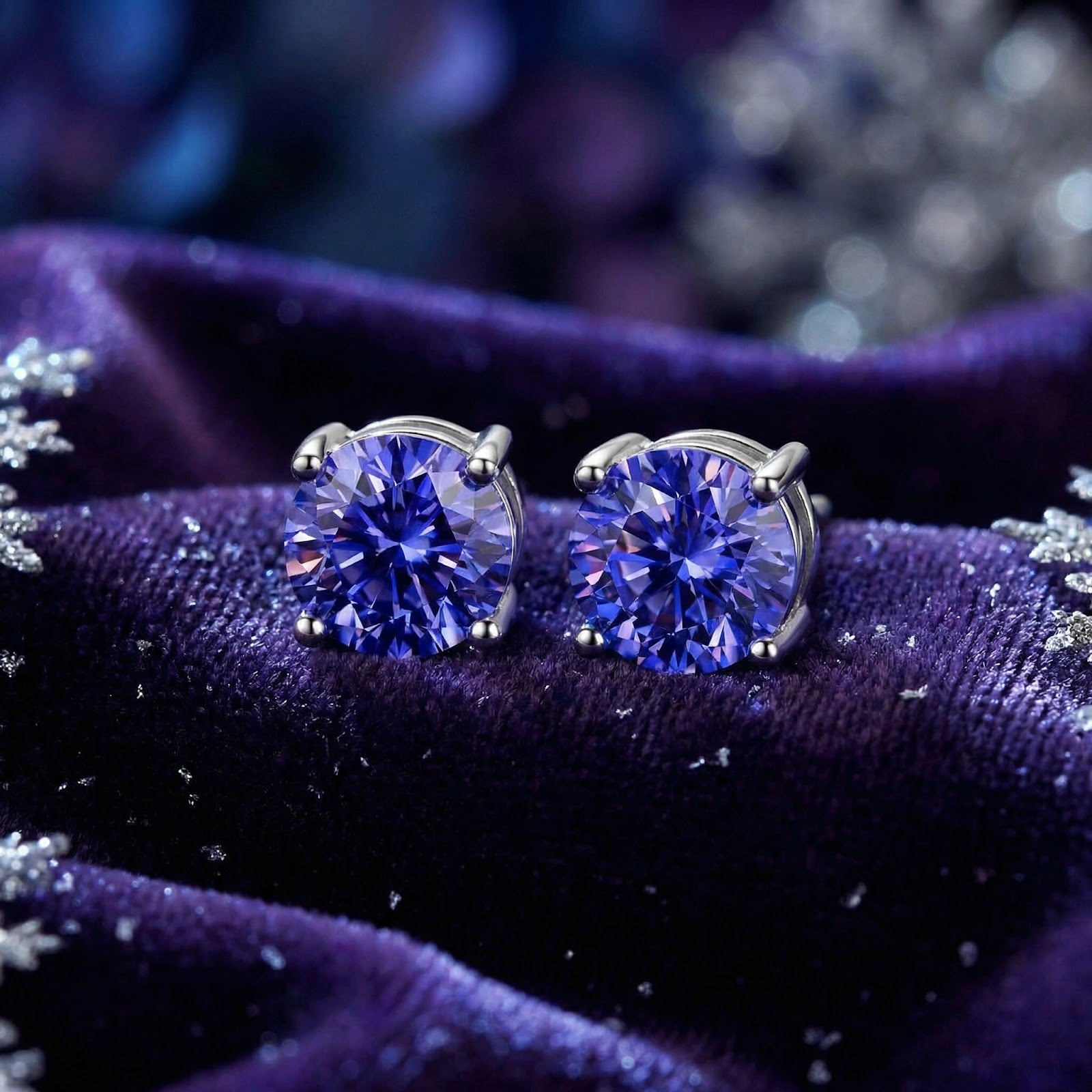Round cut simulated tanzanite S925 sterling silver stud earrings on purple velvet with snowflake props.
