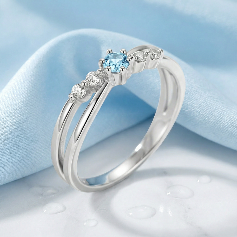 Angled view of the Sylphide silver ring featuring a round light blue simulated aquamarine and accent stones.