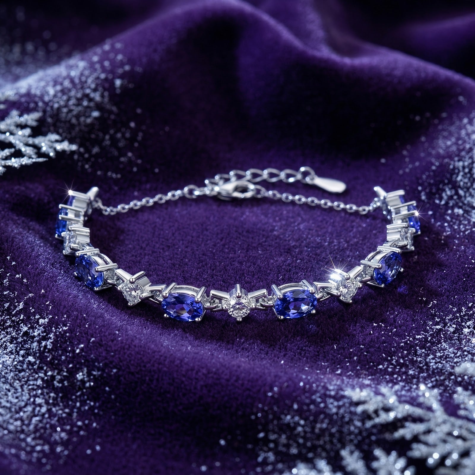 Zenelle station bracelet in sterling silver with oval-cut simulated tanzanite on purple velvet with snowflakes.