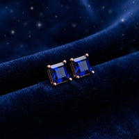 Square simulated sapphire stud earrings in 18K rose gold vermeil on a dark blue velvet background.