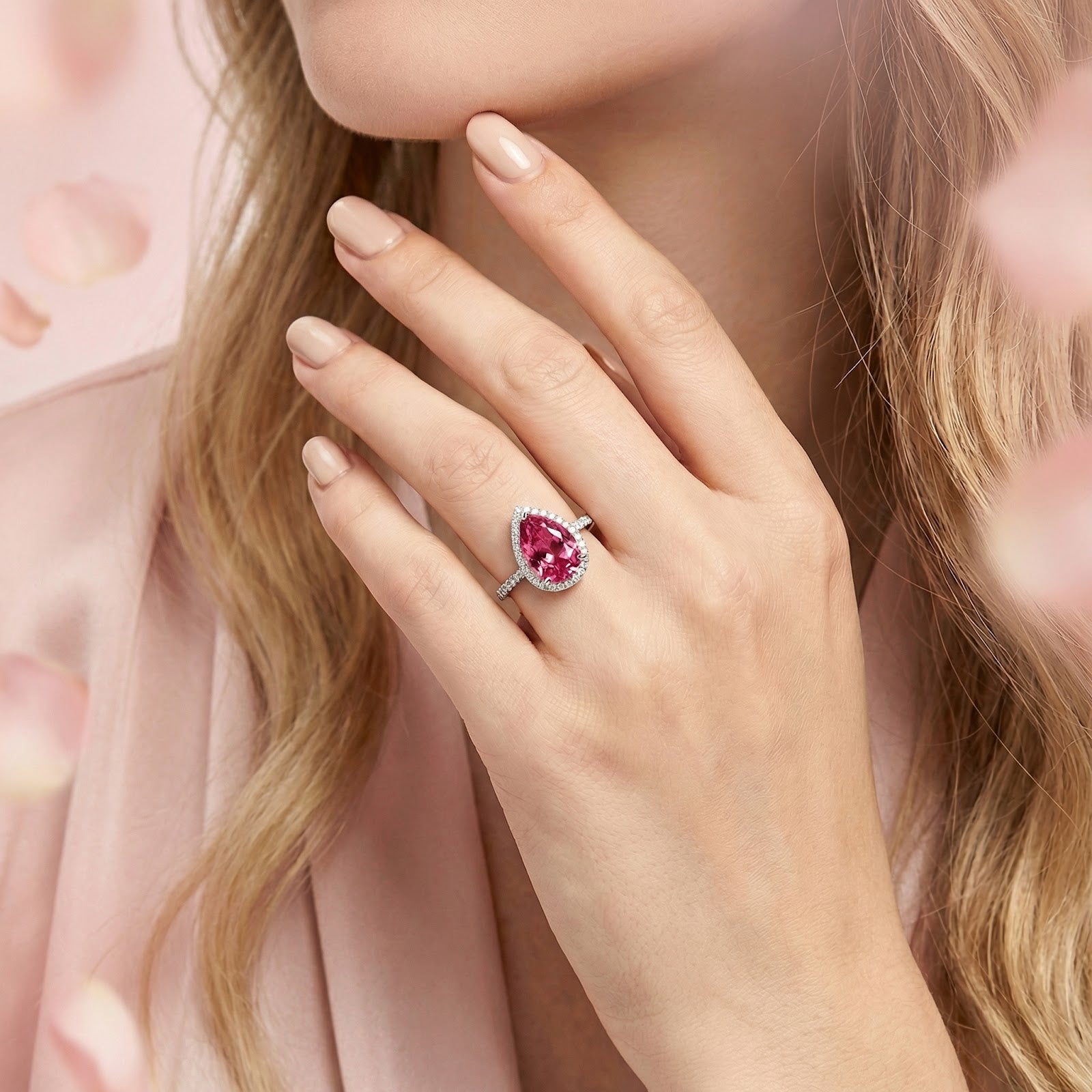 Model wearing the pear-cut pink tourmaline halo ring in sterling silver on her ring finger.