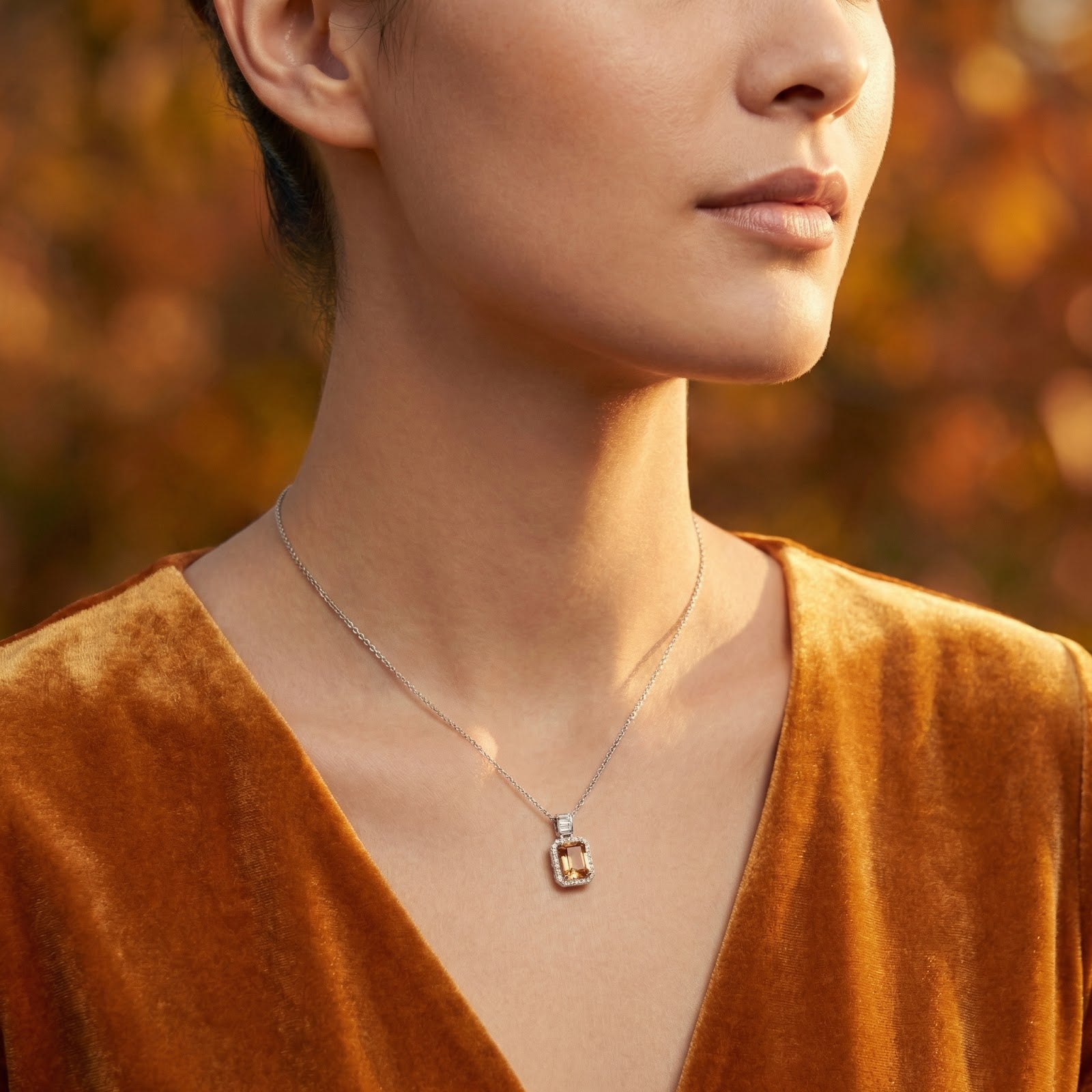 Model wearing the emerald cut simulated topaz silver necklace with a golden velvet top in an autumn setting.