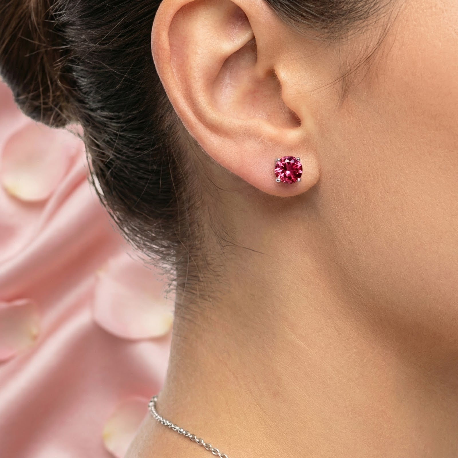 Round cut simulated pink tourmaline stud earring in sterling silver worn on a woman's ear.