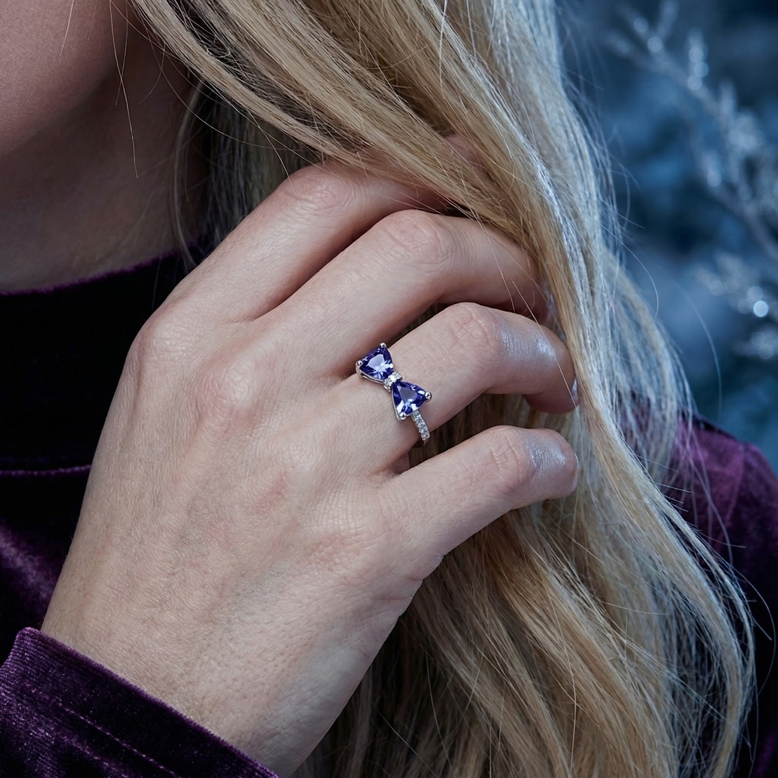 Sterling silver Evelia bow ring with trillion-cut simulated tanzanite stones shown on a model's hand.