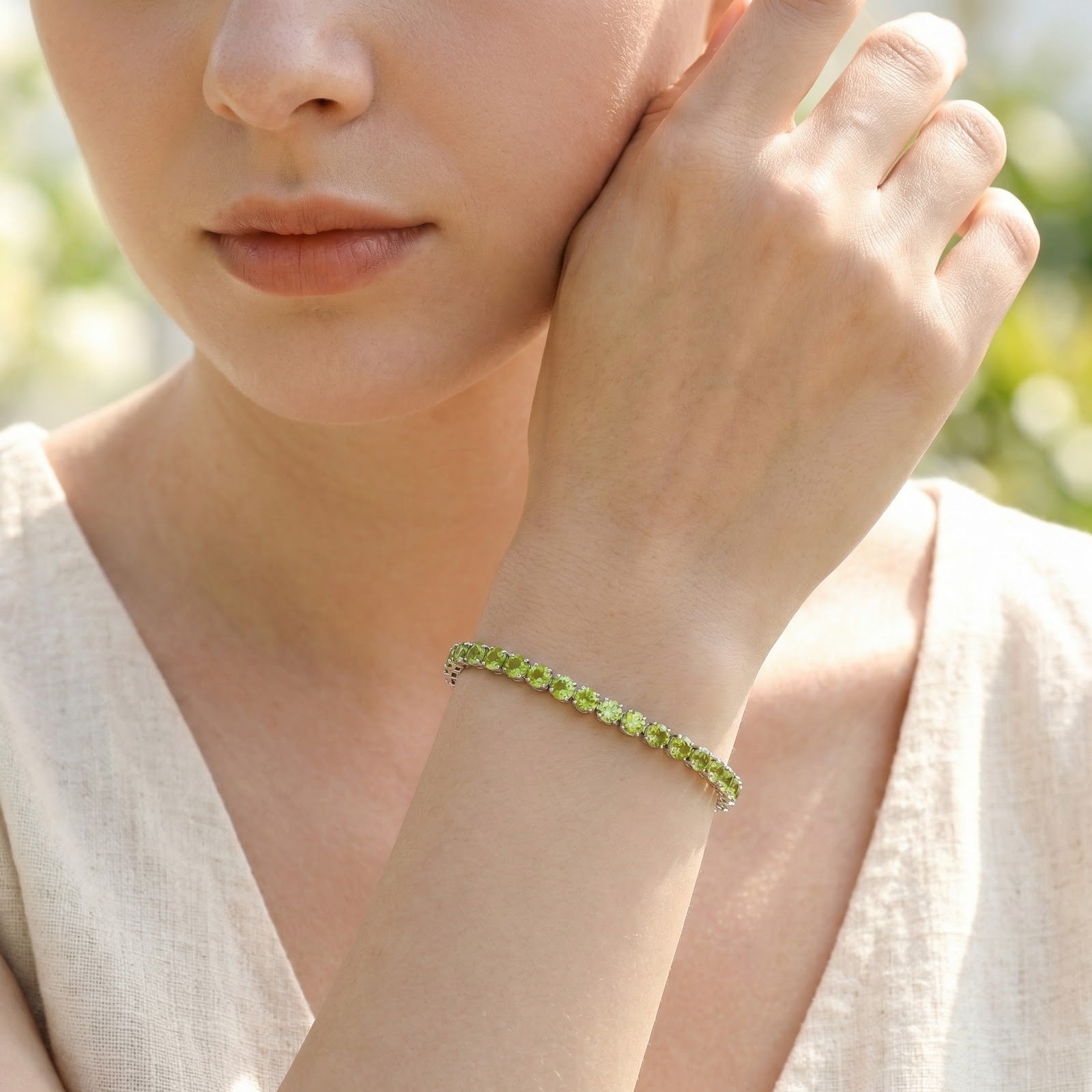 Silver finish Peridette tennis bracelet with a row of green simulated peridots worn by a model in natural light.