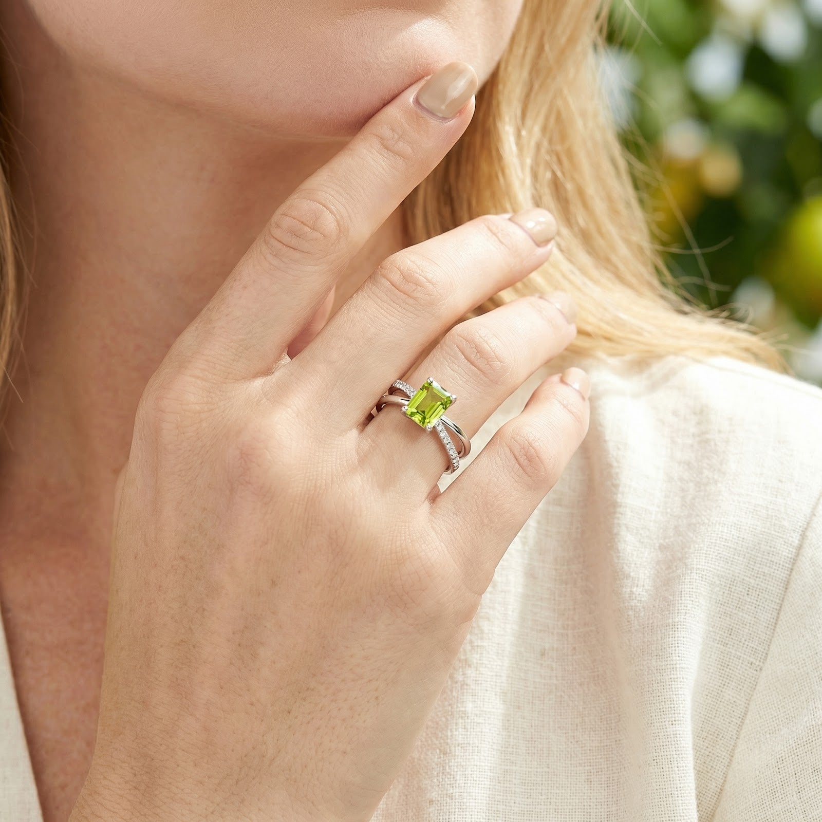 Model wearing the Aris radiant cut simulated peridot ring in S925 sterling silver on her ring finger.