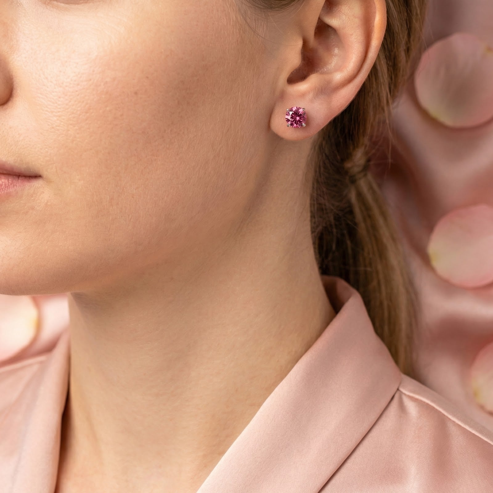 Woman wearing a round cut simulated pink tourmaline stud earring in sterling silver.