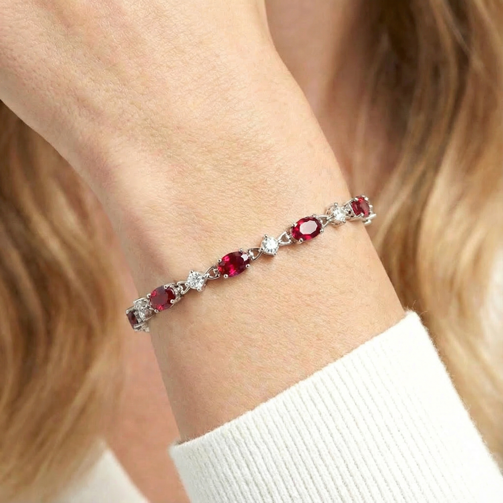 Close-up of a woman wearing the sterling silver station bracelet with oval simulated rubies on her wrist.