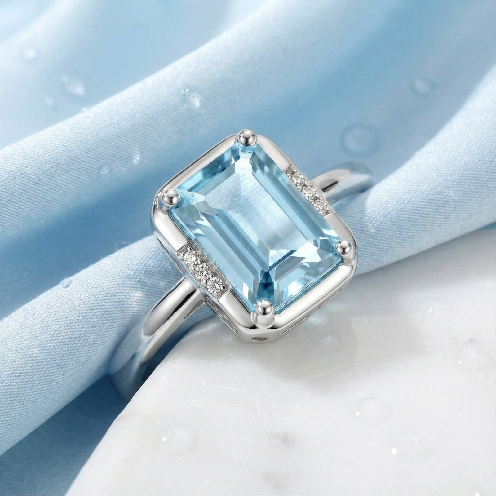 Close-up of an emerald cut simulated aquamarine solitaire ring with accent stones in 925 sterling silver.