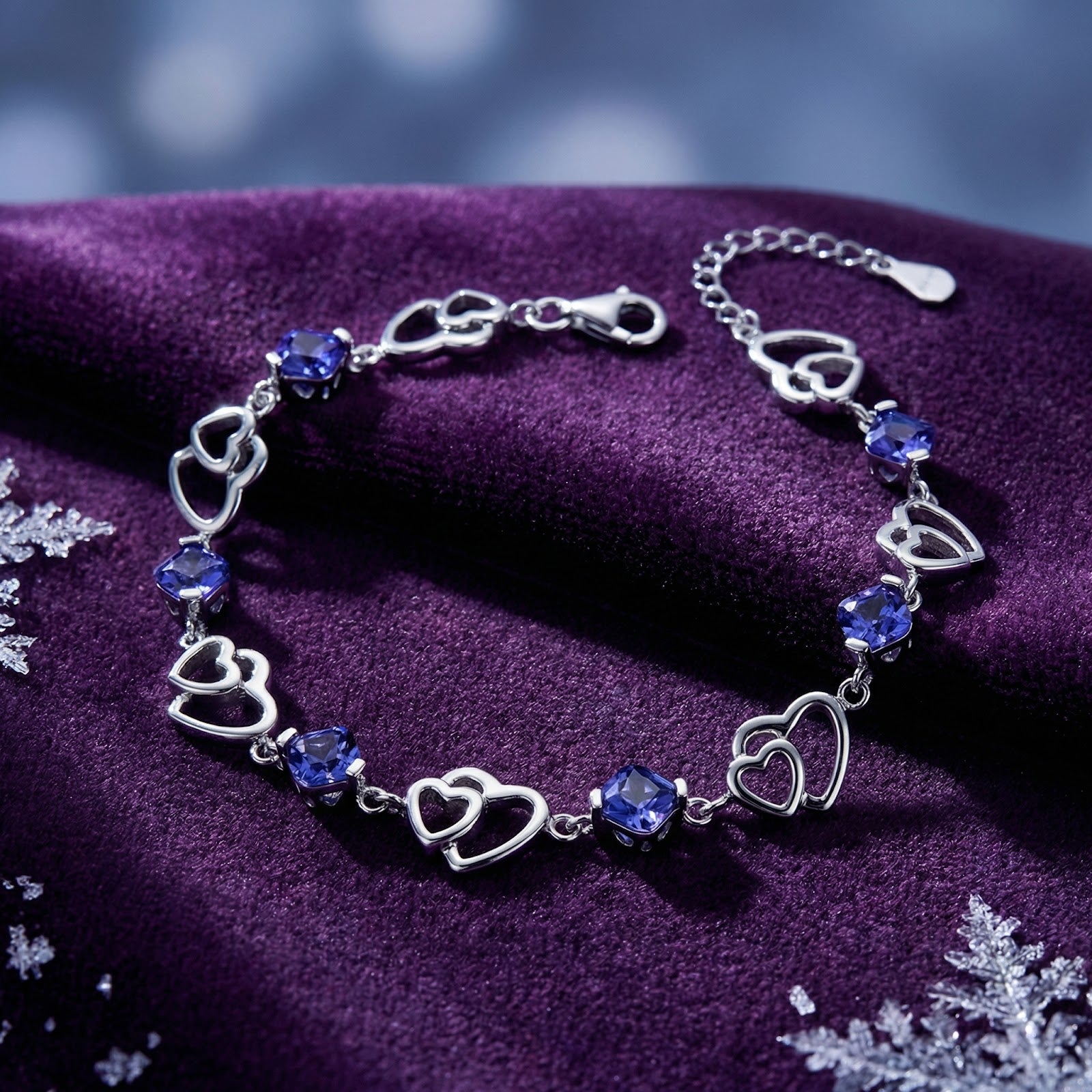 S925 sterling silver heart-linked bracelet with blue simulated tanzanite stones on purple velvet with snowflakes.