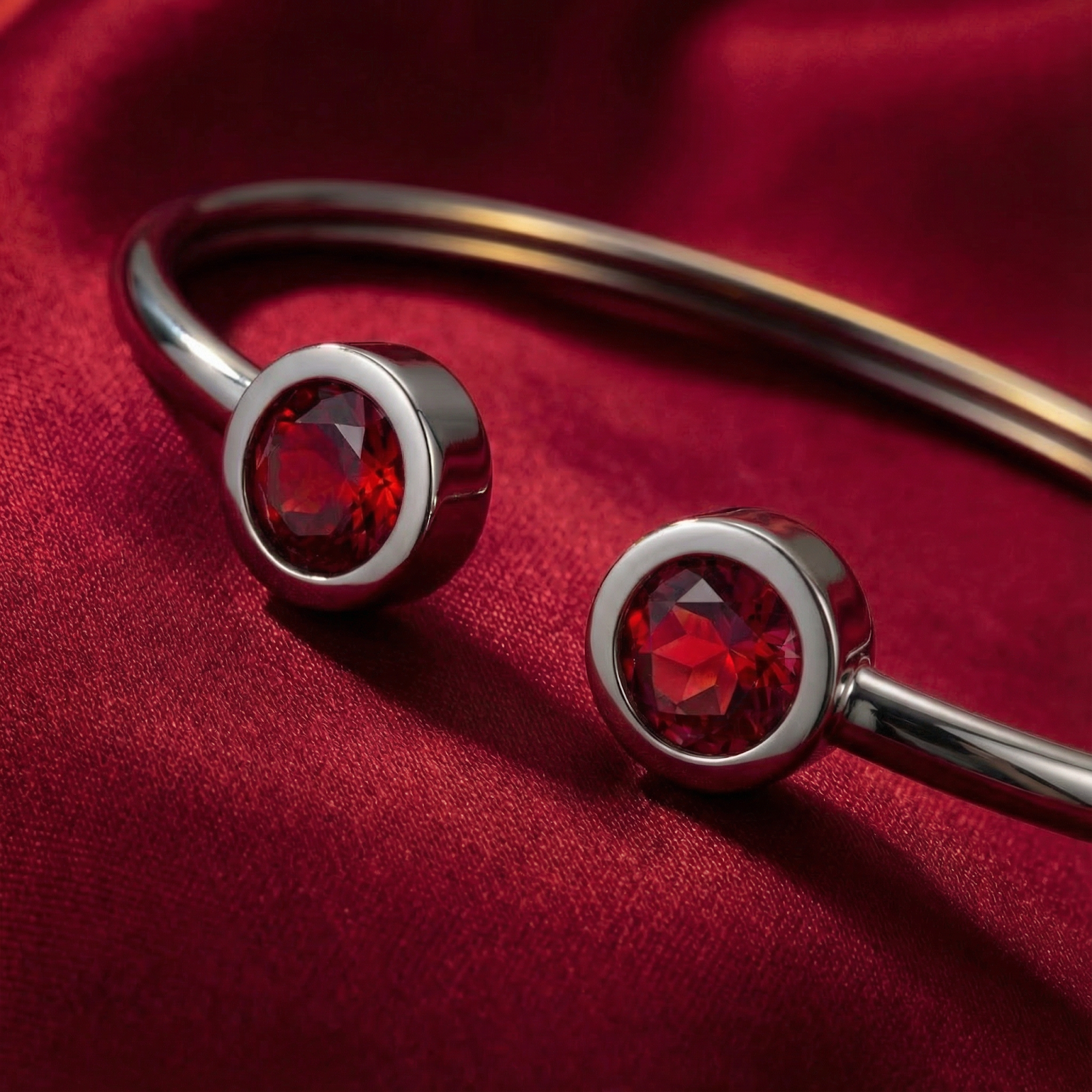 Close-up of round cut red simulated rubies in silver stainless steel bezel settings on the Selenis bangle.