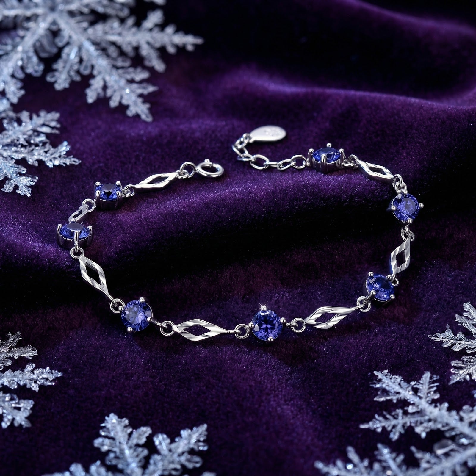 Sterling silver station bracelet with round simulated tanzanite stones on purple velvet with snowflakes.